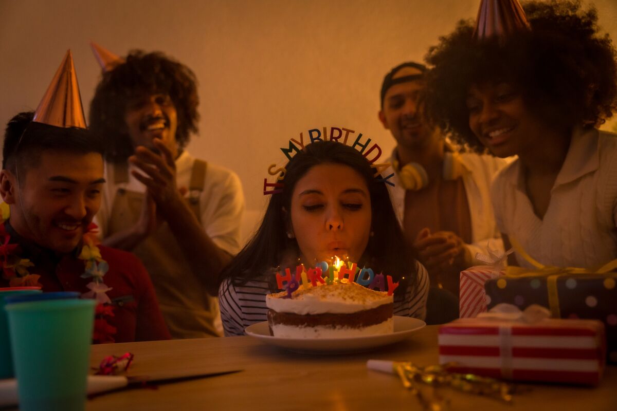 Friends round a birthday cake with candles