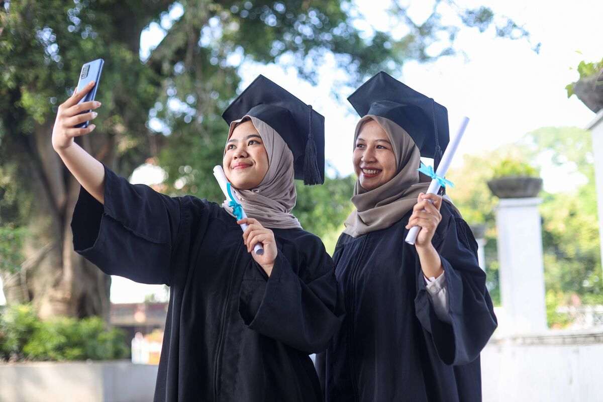 Two graduates taking a selfie in caps and gowns